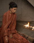 Woman in a brown embroidered outfit sitting by a fire