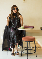 Woman in a black dress sitting at a table in a cafe.