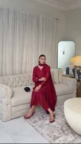 Woman in a red dress sitting on a beige sofa in a stylish living room.