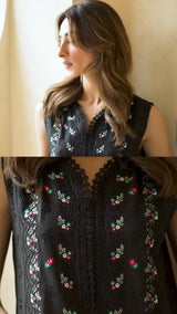 Black embroidered top worn by a model against a neutral background