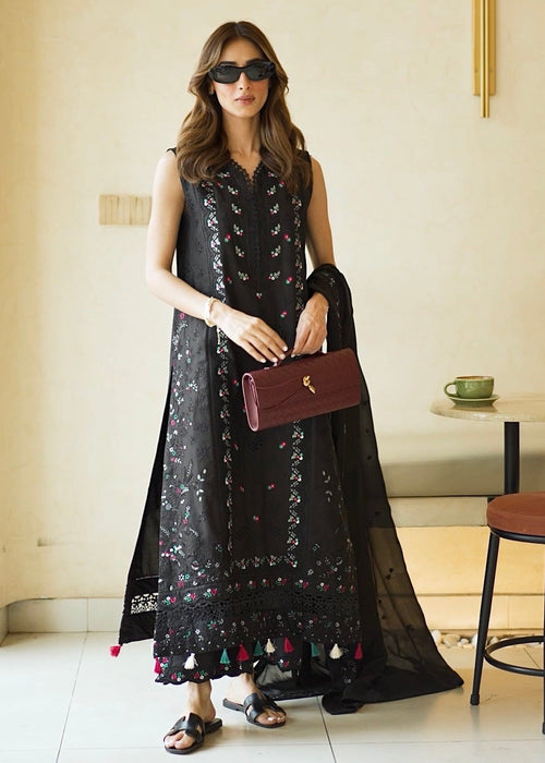 Woman in a stylish black outfit with sunglasses and a handbag in an indoor setting.