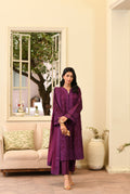 Woman in a purple outfit standing in a living room with a mirror and decor.