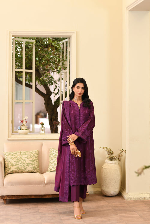 Woman in a purple outfit standing in a living room with a mirror and decor.