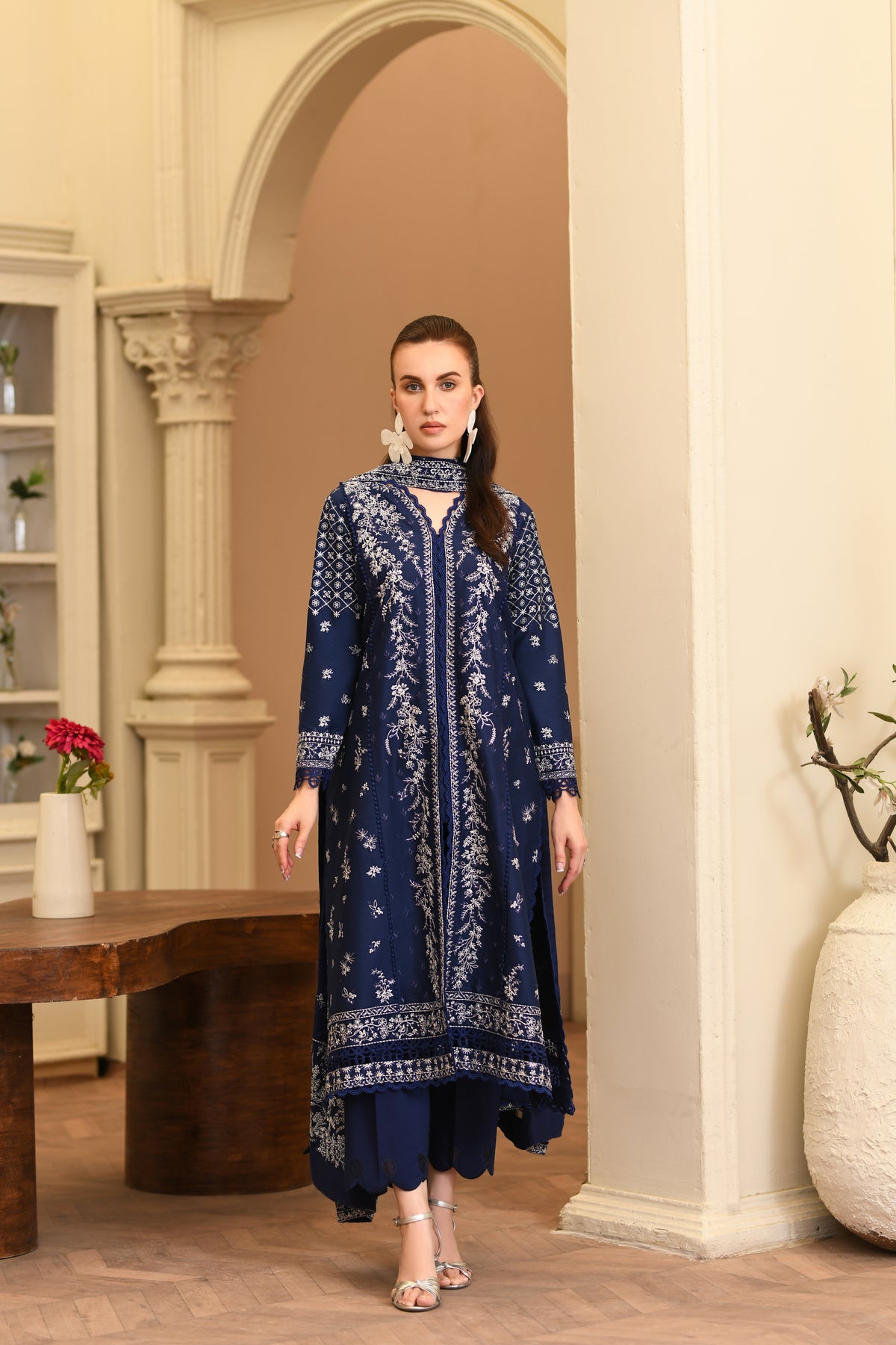 Woman wearing a blue embroidered outfit in an elegant indoor setting