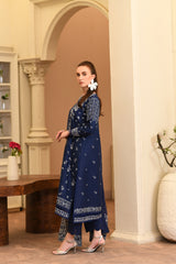 Woman in a blue floral dress standing in an elegant room with decorative elements.