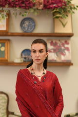 Woman in a red dress standing in a room with decorative shelves and flowers.