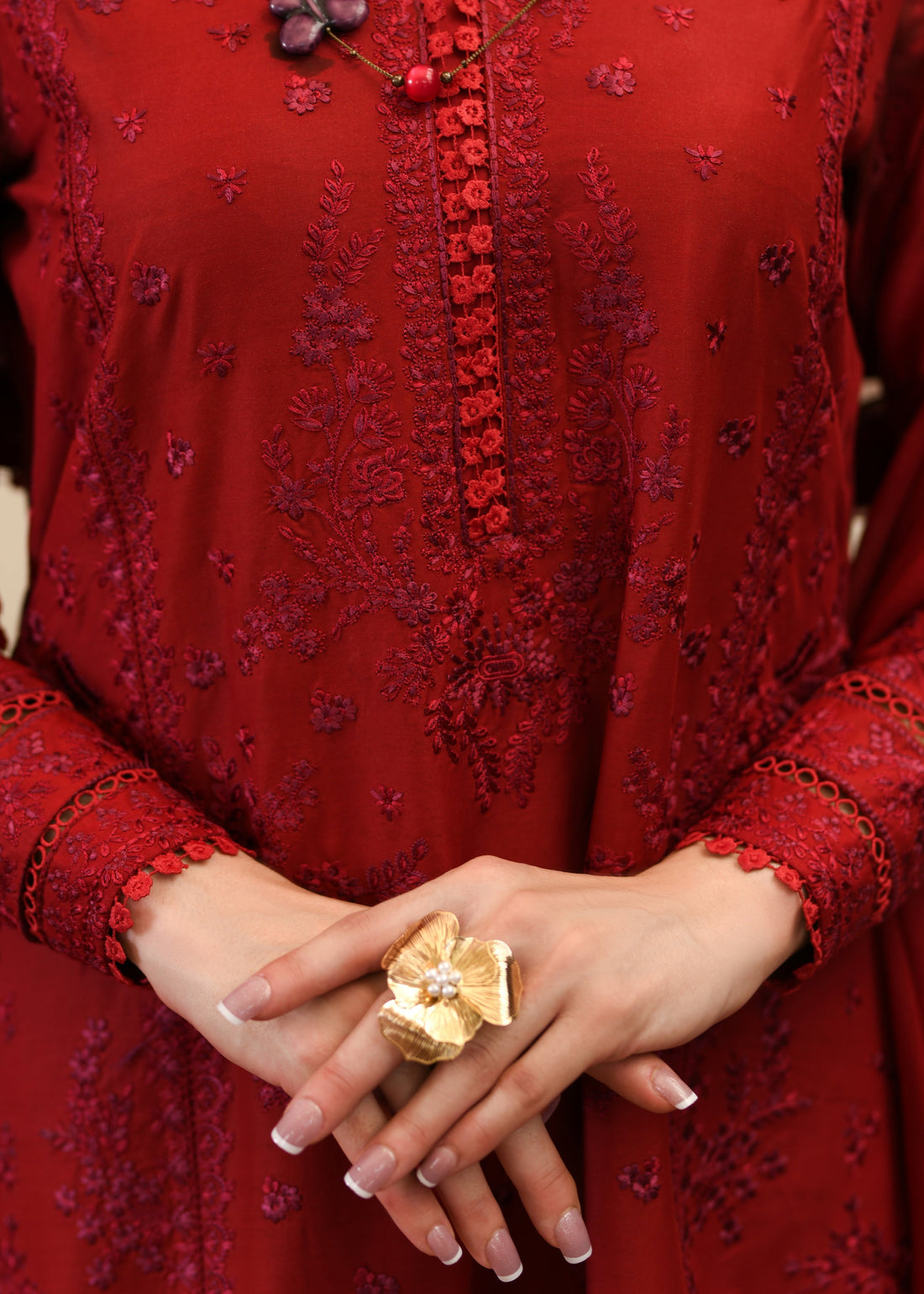 Woman in a red outfit standing in a room with decorative shelves and chairs.
