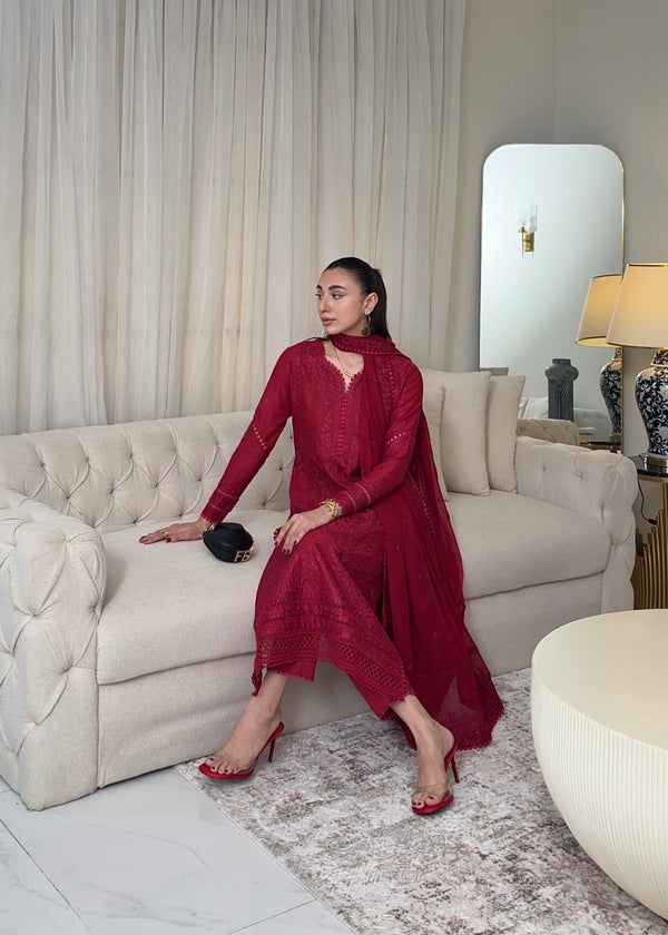 Woman in a red dress sitting on a beige sofa in a stylish living room.