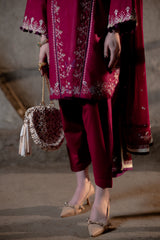 Person wearing a red embroidered outfit with a matching handbag on a neutral background