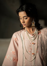 Woman wearing traditional embroidered attire with jewelry against a dark background