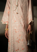 Person wearing a light pink embroidered dress with floral patterns, holding a black handbag.