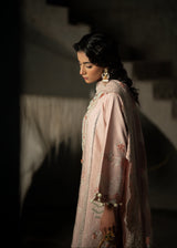 Woman in a traditional outfit with intricate designs and jewelry against a dark background