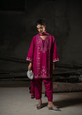 Woman wearing a magenta embroidered outfit against a dark background
