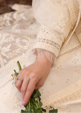 Close-up of a hand holding greenery in a lace dress with intricate details.